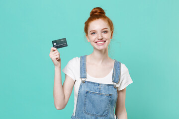 Smiling young readhead girl in casual denim clothes isolated on blue turquoise wall background...