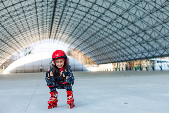 little cute happy girl rollerblading in a big hangar