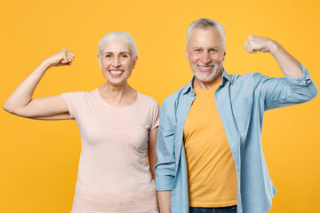 Smiling elderly gray-haired couple woman man in casual clothes posing isolated on yellow background...