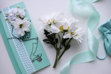 greeting card. envelope, white flowers and jewelry. wedding bouquet on blue background