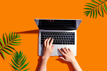 Person using a laptop computer with tropical leaves from above