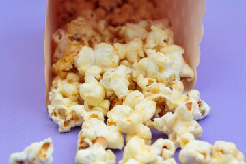 Popcorn falling out of the box on purple background