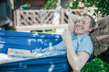 A man is resting and reading in a hammock. Day off and relaxation