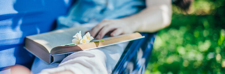 A man is resting and reading in a hammock. Close-up
