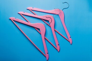 Obraz na płótnie Canvas Pink empty wooden clothes hangers on pastel blue background.