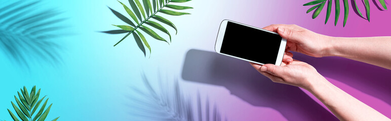 Smartphone with tropical palm leaves and shadow - flat lay