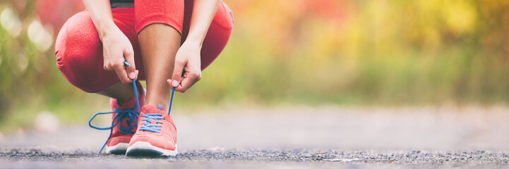 Exercise and sport running shoes runner woman tying laces getting ready for summer run in forest park panoramic banner header crop. Jogging girl exercise motivation heatlhy fit living. - obrazy, fototapety, plakaty