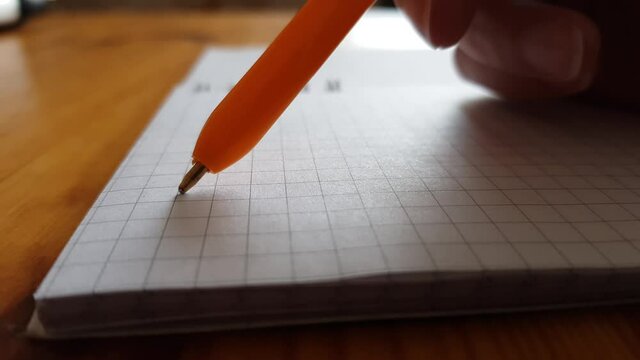 hand with pen over a blank sheet of notebook, hesitant thoughts to write or not.