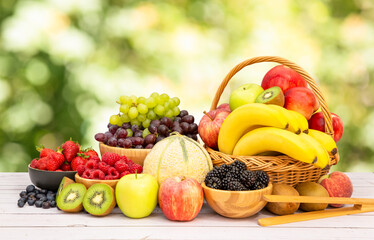 Group Healthy fresh fruit in a wooden basket, With vitamins c from bananas, kiwi, grapes, raspberries, blueberries, and blackberries, good for the body and diet food on the table in nature background.