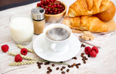 Breakfast in the morning with black coffee cup with bread with Croissant and fruit on the wooden table.