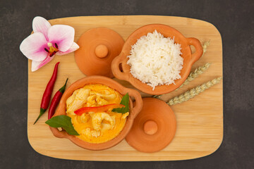 Chicken Panang Curry with Rice is Thai food sauce curry and basil leaf and coconut milk put on Terracotta pot on a banana leaf in wooden background