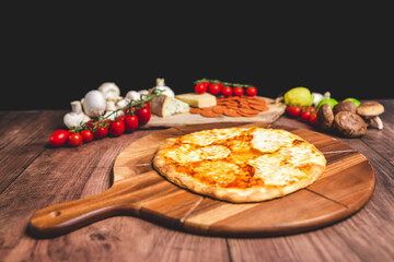 Homemade freshly baked Pizza Margherita with melted mozzarella on the top on a wooden board with lots of decorative vegetables. Concept of fresh hot pizza with free space for your text/decorations.
