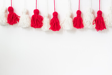 brushes from yarn of red and white color on a white background. Space for copy space. DIY yarn brushes. Garland. Garland of yarn. Pampushki from yarn. Children's creativity