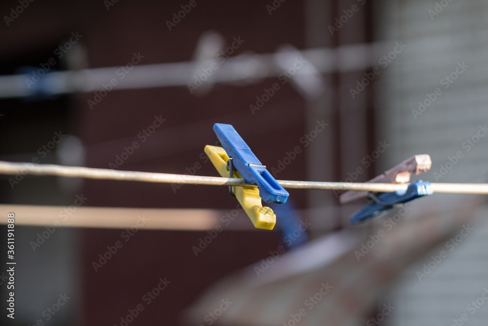 Poster vertical shot of a yellow and blue hanging laundry clip with blurred background