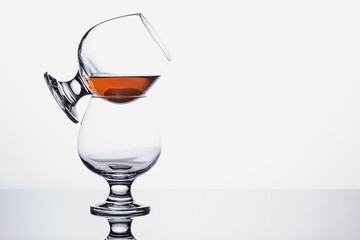 two transparent glass cognac glasses on top of each other with cognac isolated on white background. Pyramid of groceries. White background. Whiskey / Brandy / Cognac / Rum. A glass with a strong drink