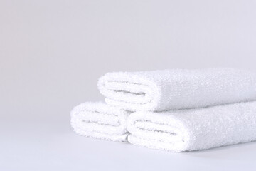 Three white neatly folded terry towels on a light background.