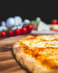 Homemade freshly baked Pizza Margherita with melted mozzarella on the top on a wooden board with lots of decorative vegetables. Concept of fresh hot pizza with free space for your text/decorations.