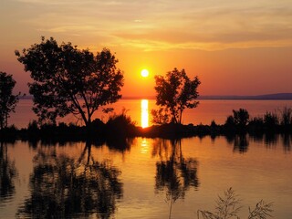 Balatonmáriafürdő, Hungary - June 27, 2020: Silhouette of a boy fishing at sunset on a canal in the south coast of the lake Balaton, Hungary