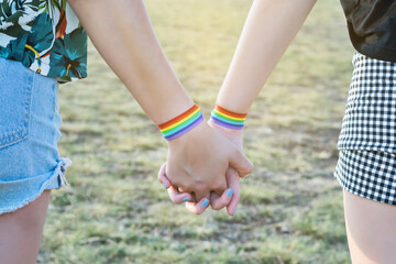 Fototapeta na wymiar Close-up of two hands connected. Interlocking hands with lgtbi bracelets.