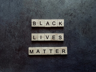 Inscription of wooden letters black lives matter on a dark background.