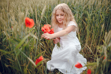 beautiful little girl with blond hair in a white dress in the background of a beautiful field. Girl...