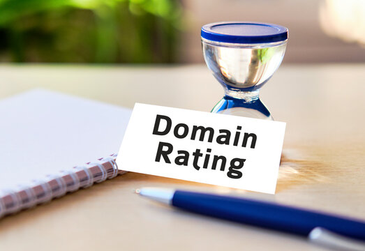 Domain rating business seo concept text on a white notebook and hourglass clock, blue pen, green leaves of flowers