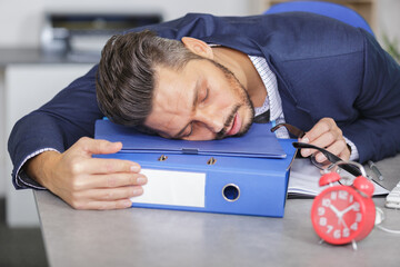 businessman asleep on folder in the office