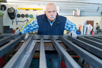 senior metalworker controls some metal bars in steel mill