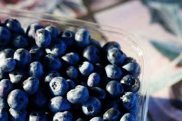 Fresh blueberries in a transparent tray on wooden table, top view