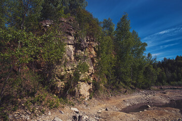 Obraz premium Rocky hill. View of sandstone, remains of a mine. Rocky hill covered with trees and vegetation.