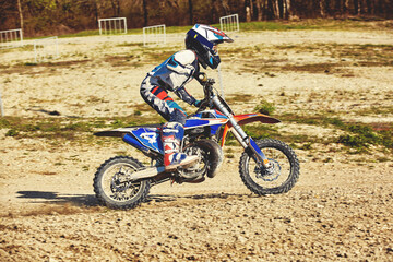 Fototapeta premium Motocross concept, a biker goes off-road making extreme skiing. In pursuit of adrinalin, sport concept. Dangerous sport.
