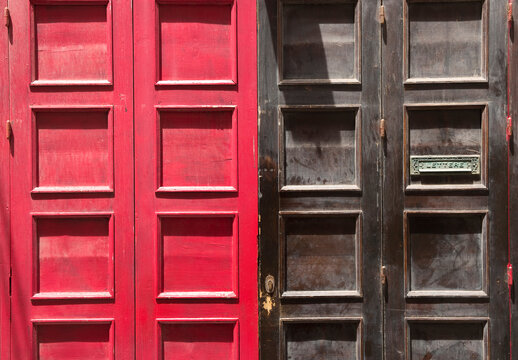 A Double Panelled Door In Red And Black Wood With A Rustic And Vintage Patina And Feel And A Green Postbox.