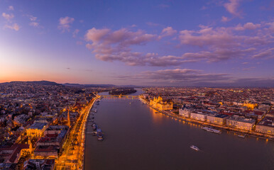 Aerial drone shot of Danube river with lighted quai with purple sky during Budapest sunset