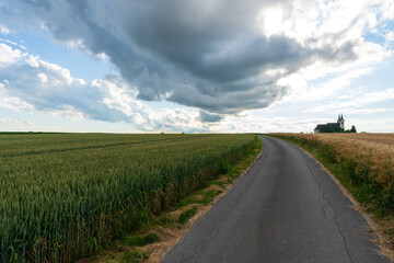 Weg zur Walfahrtskirche Heiligenkreuz bei Kremsmünster in Oberösterreich mit Regenwolken und Getreidefelder