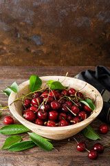 Sweet cherry with leaves in wooden bowl. Fresh ripe cherries. Cherry fruit