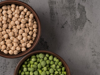 Green peas and chickpeas in a brown pot. The gray background.