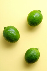 Fresh juicy limes on a yellow uniform background. Citrus Vitamin C Healthy Eating and Lifestyle