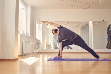 Athletic young man doing exercise with yoga blocks