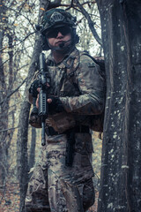 Fototapeta premium portrait of a soldier with a gun in the forest of Battlefield/army uniform with a weapon.