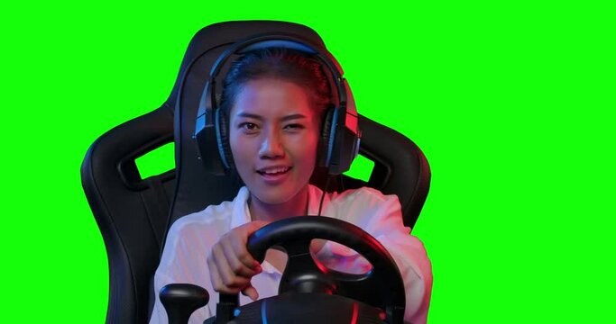 POV Excited young asian pro cybersport gamer in headset sitting in the racing seat simulator cockpit with steering wheel and playing in car racing online video game over green screen background.
