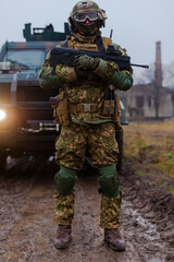 Obraz premium soldier is ready to shoot against the background of an armored car and the included headlights