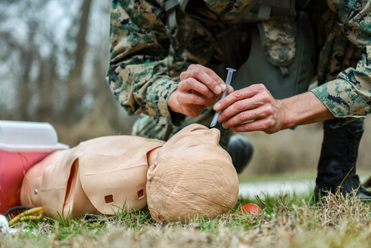 A U.S. Marine demonstrates providing first aid to an injured person on a training plastic doll