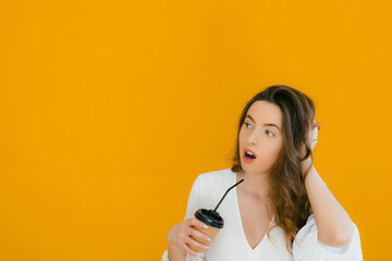 Portrait of a happy woman holding take away coffee cup and looking at camera isolated over yellow background