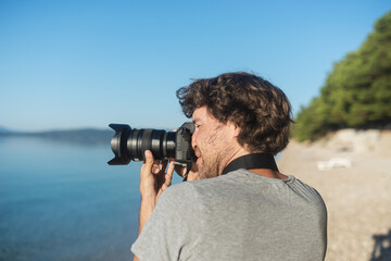 Young male photographer taking photos of beautiful sea and nature