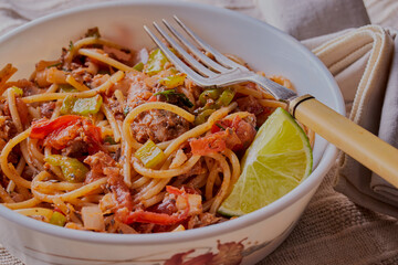 Spaghetti and sardines in a bowl with a lime slice.