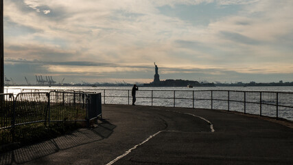 man looks out at Statue of Liberty