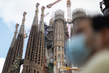 Fototapeta premium Young man with a medical face mask in front of the Sagrada Familia basilica in Barcelona, Spain during the Coronavirus pandemic. - Illness, Covid-19, Quarentine. - The new normal.