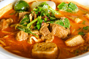 Selective focus of green leaves on mutton curry noodle during breakfast.
