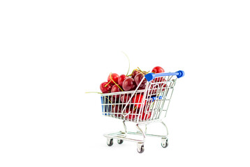 Sweet cherries. Berries are poured into a mini shopping cart from the supermarket. Red cherries, ripe berries on a white background.
