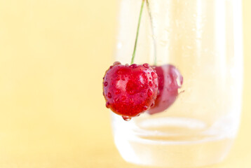Sweet cherries. Red cherries hang on a transparent glass. Ripe berry. Bright summer background for presentations and graphic works.